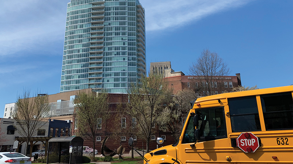 A bus driving in Durham. In the background, a large tower reaches for the sky