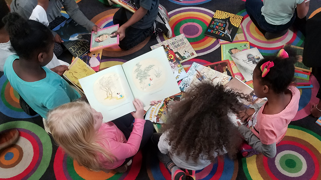 overhead shot of children reading books on a rug