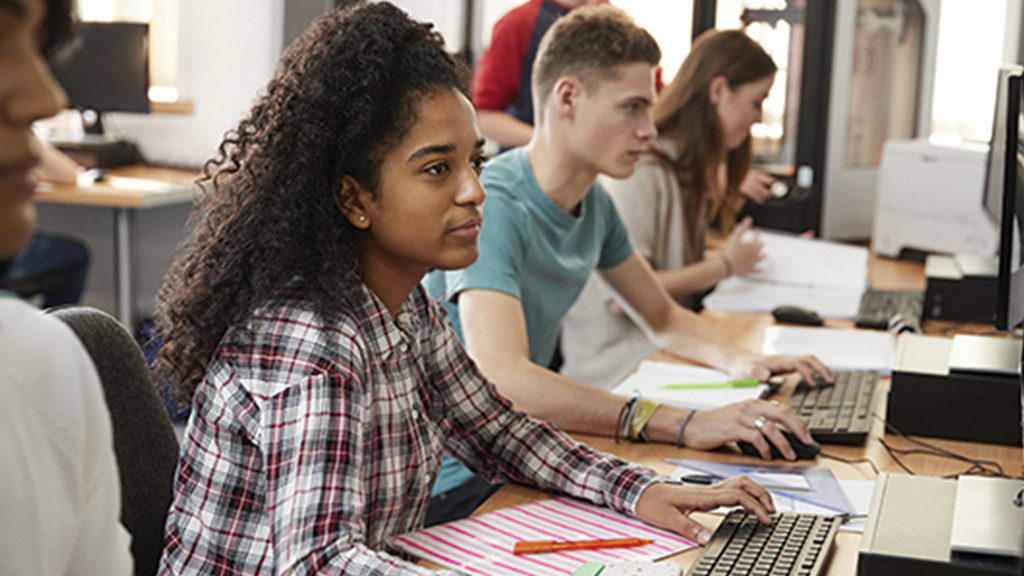 Student sit in a classroom and use desktop computers