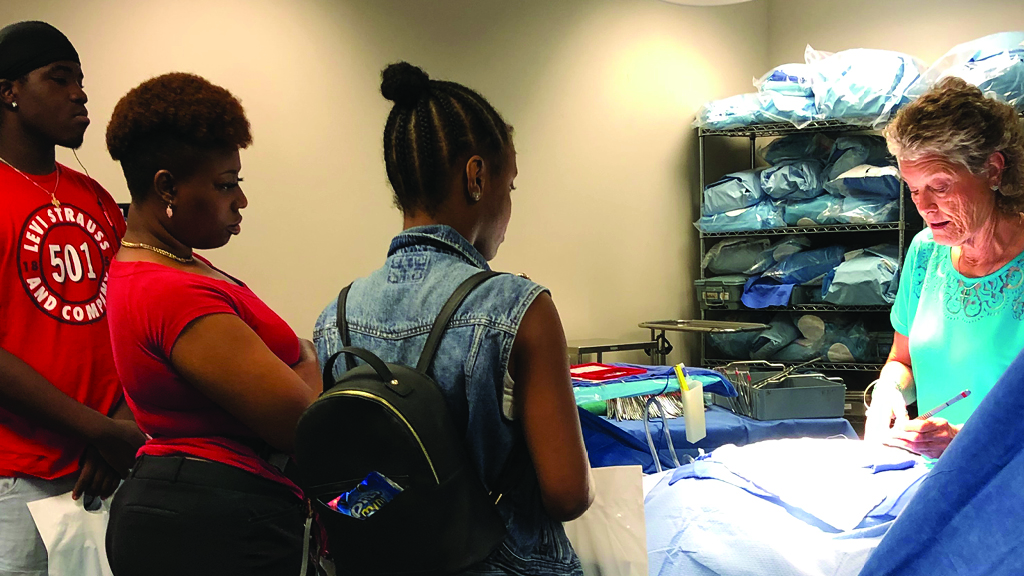 An instructor shows three students medical equitment