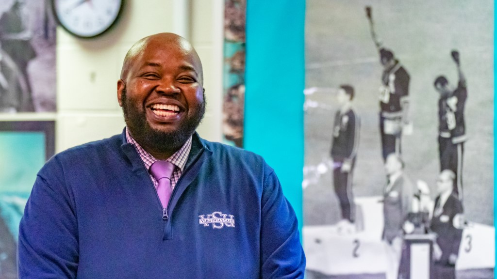 Rodney Robinson laughs and smiles at the camera, standing in a classroom