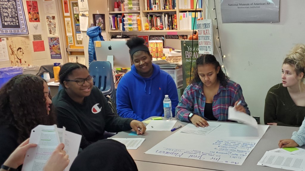 Students discuss their work around a table