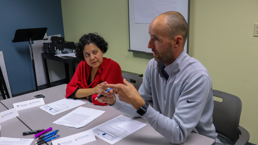 Two adults animatedly talk at a table