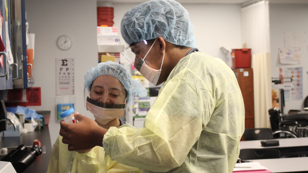 Students with medical masks examine a bottle