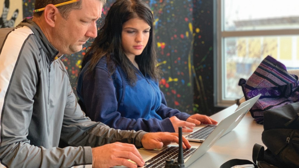 a student and teacher work on a laptop