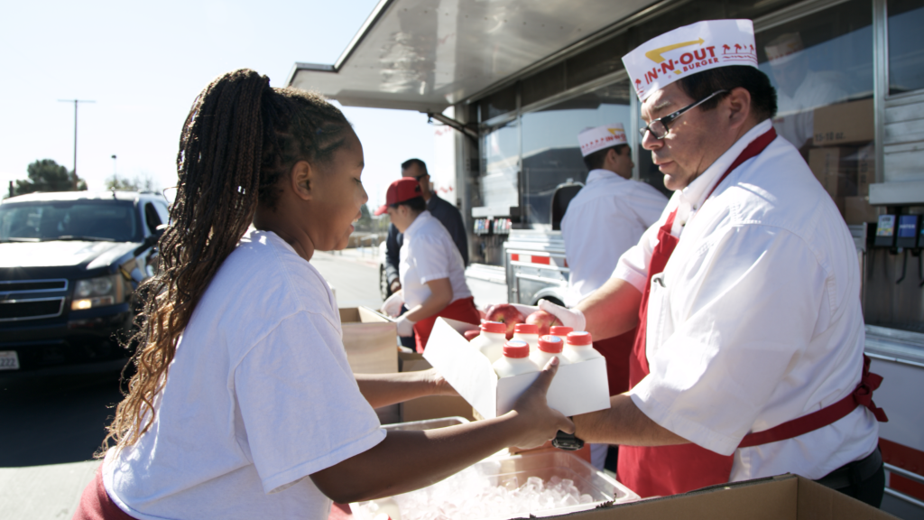 a volunteer hands out milk to a student