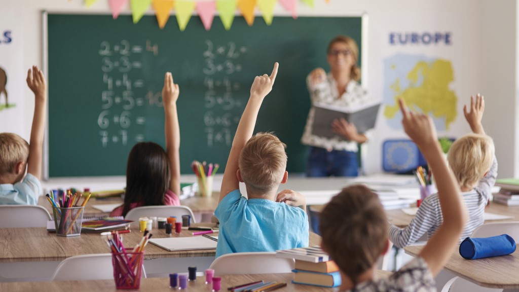 students raising their hands in a classroom