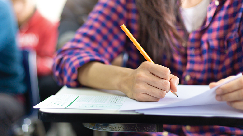 a close up shot of a student writing at her desk