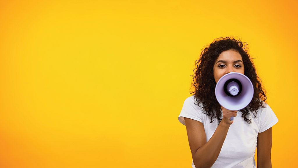 a woman holds up a loudspeaker to her mouth