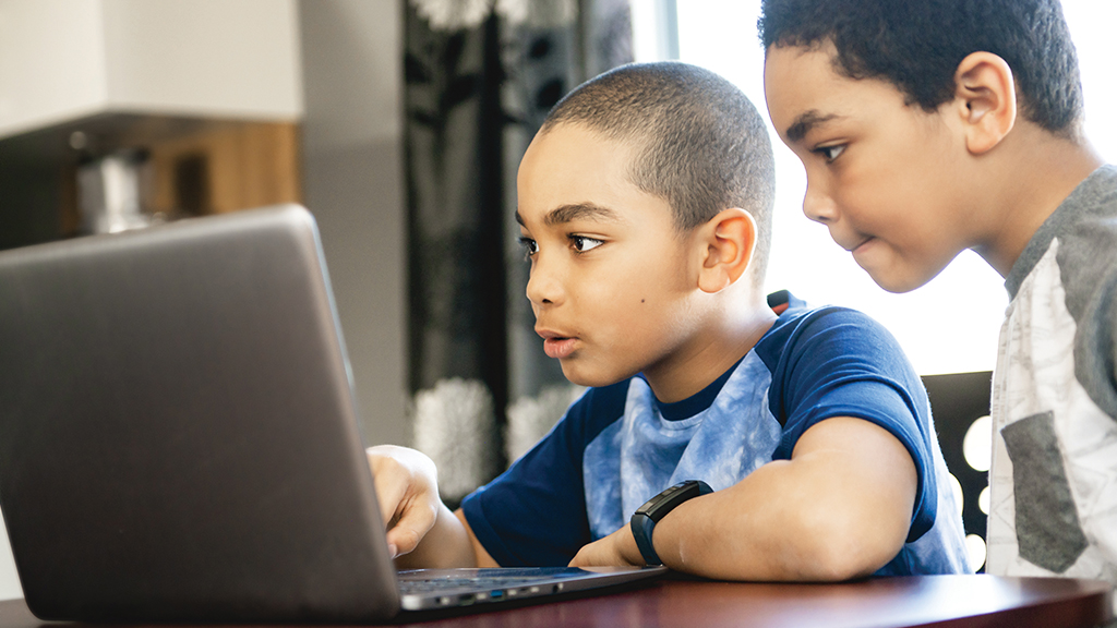 two boys use a laptop