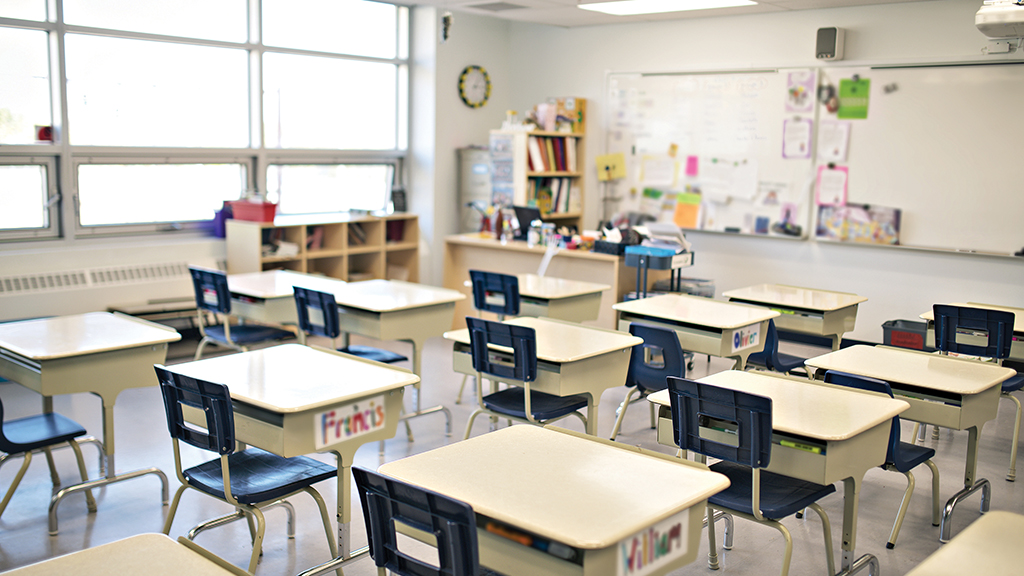 an empty classroom, the desks arranged in rows