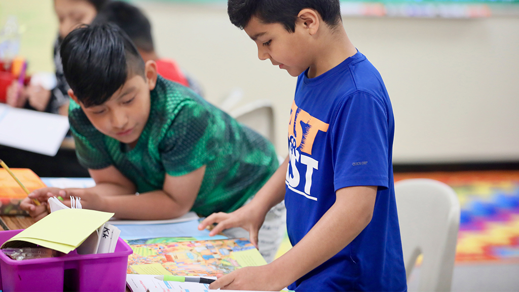 two young students work together at a table