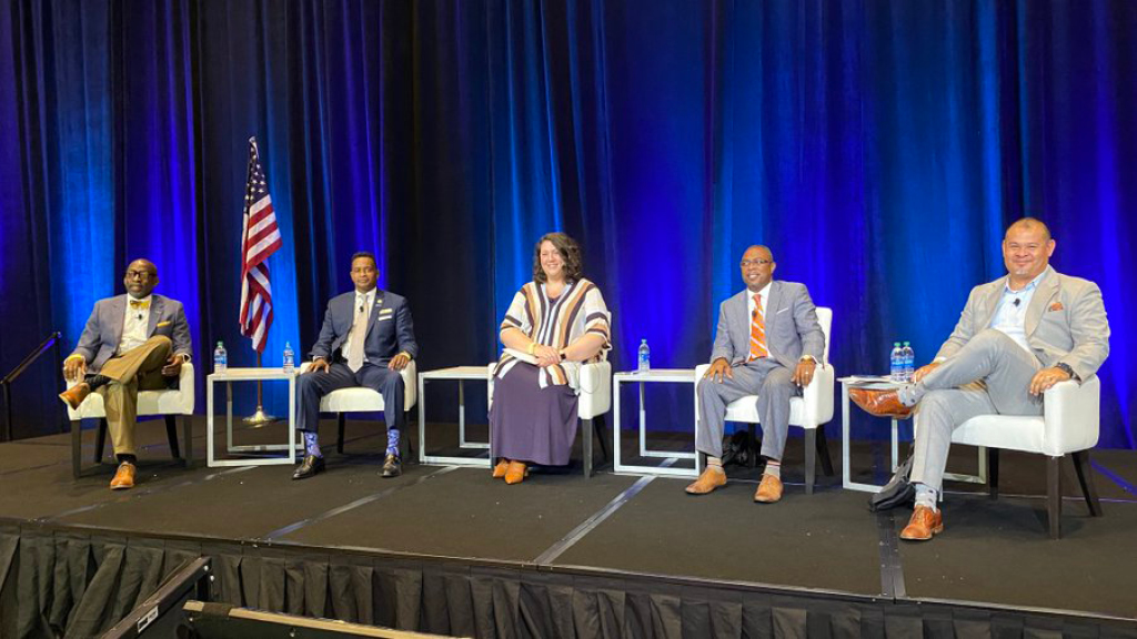 five school board leaders sit on stage