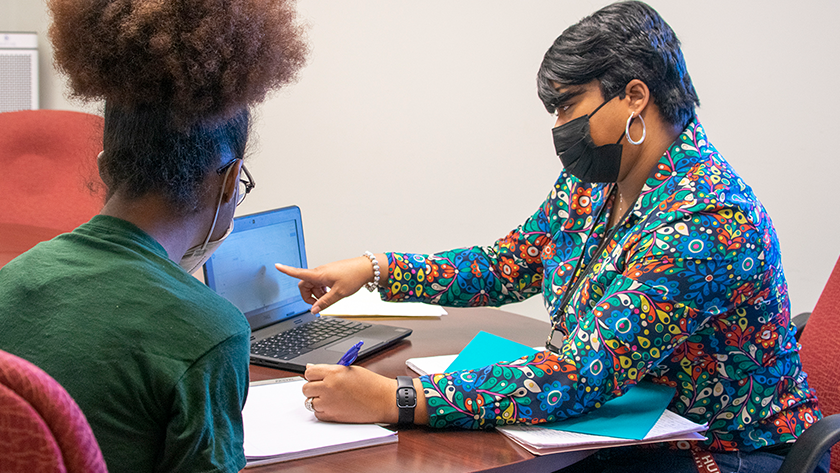 A student and school support specialist look at a computer screen 