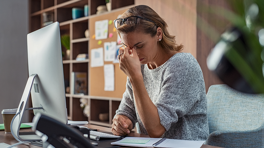 A woman looks at a computer and rubs her eyes