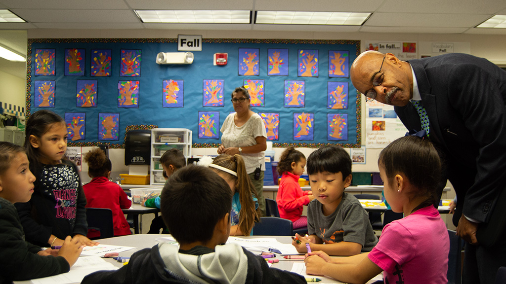 An education researcher chats with young school students