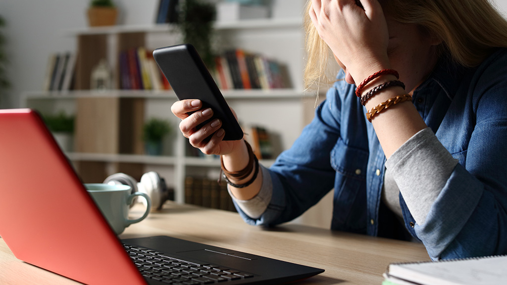 Teen girl looks worried as she looks at a mobile phone.