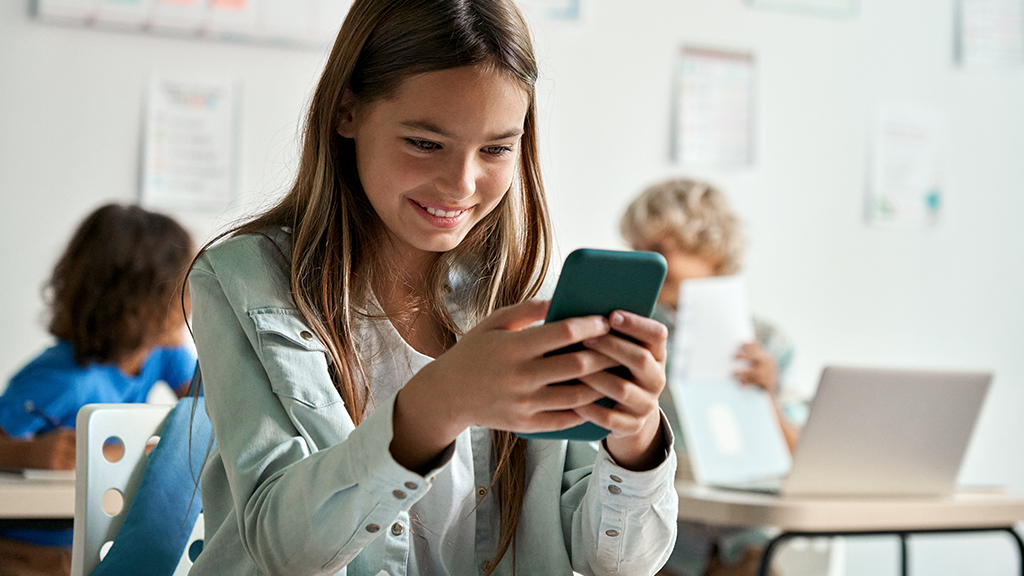 Middle school girl looks at her cellphone in class