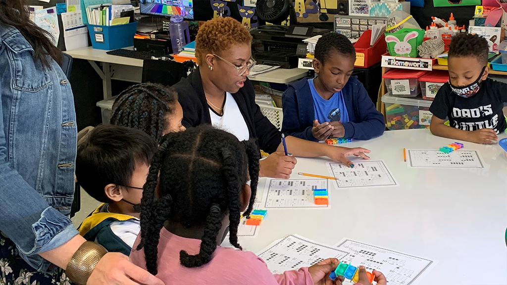 A high school student and aspiring teacher teaches a lesson to a group of elementary-age students. 