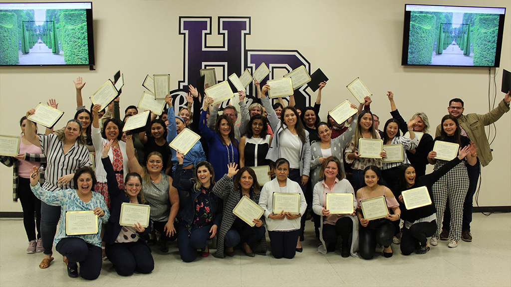 A group of adult students celebrate graduation from a hotel-industry training program. 