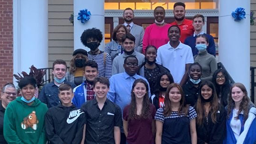 A group of high school students pose in front of City Hall. 