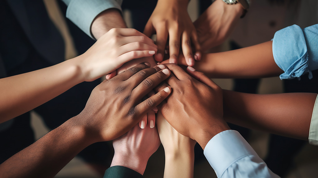 A collection of 10 hands reflecting different skin tones connect in a sign of unity.